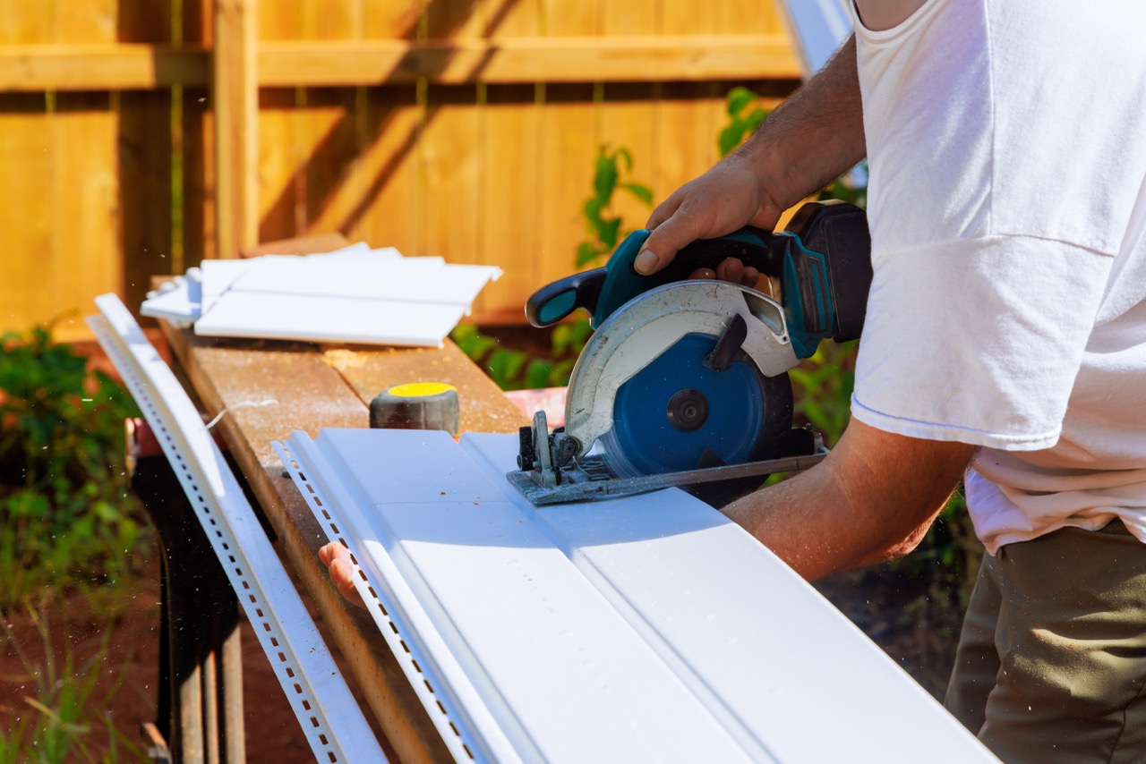 Prior to installing vinyl siding panels on a craftsman facade, vinyl siding panels are cut to desired sizes during construction home insurance